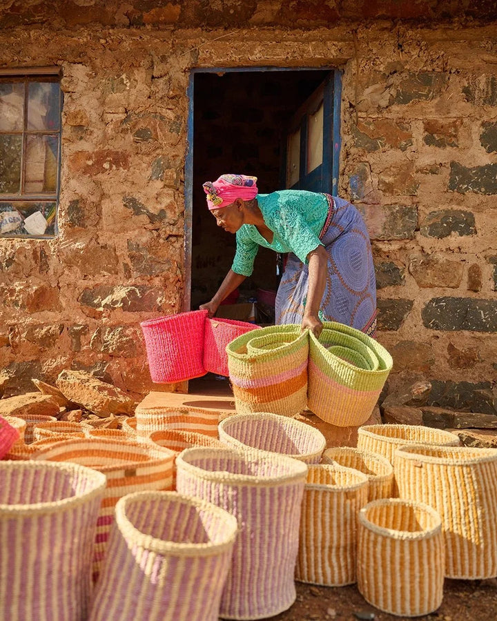 The Basket Room — artisan arranging colourful woven baskets outside a workshop