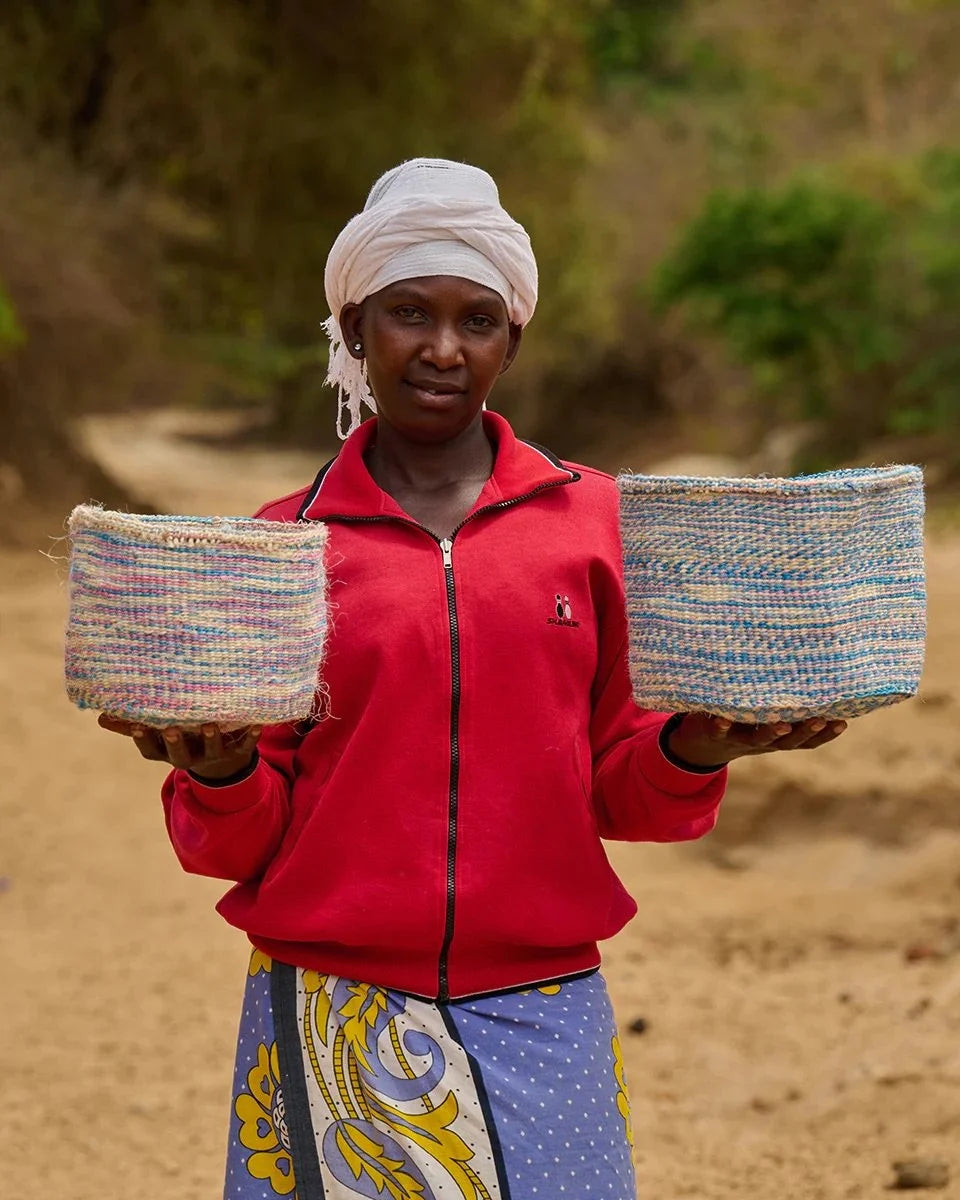 KWENYE by The Basket Room — artisan holding two blue and pink baskets; sizes not specified