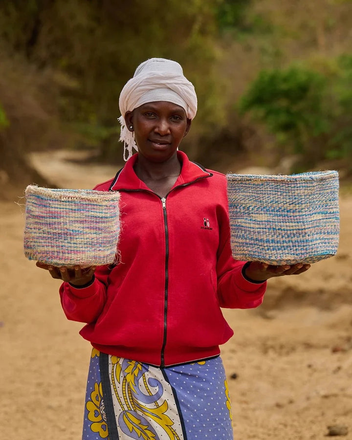 KWENYE by The Basket Room — artisan holding two blue and pink baskets; sizes not specified