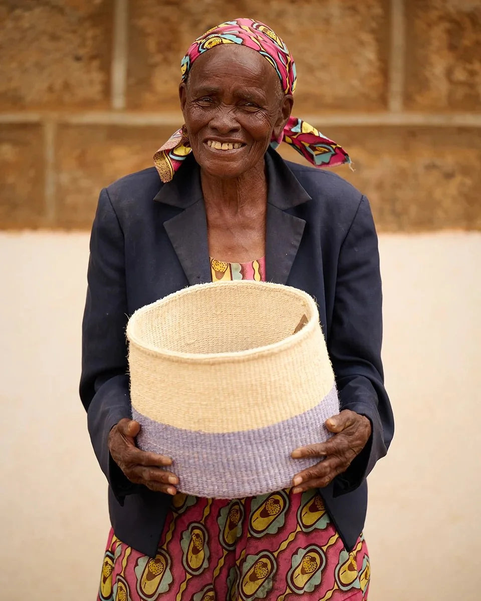 JADALA by The Basket Room — artisan holding a lavender and natural basket; size not specified