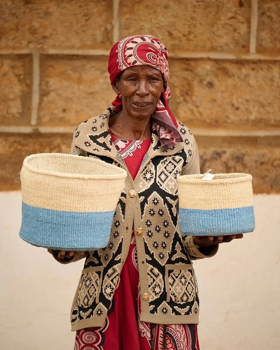 ZURI by The Basket Room — artisan holding two powder blue and natural baskets; sizes not specified