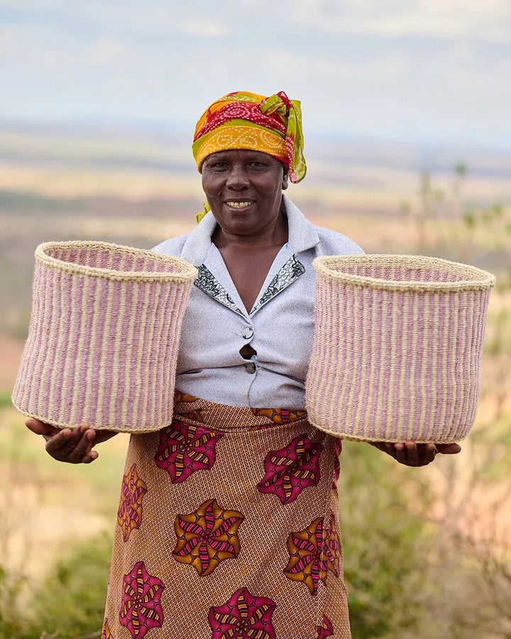 UMEME by The Basket Room — artisan holding two lavender pinstripe baskets; sizes not specified