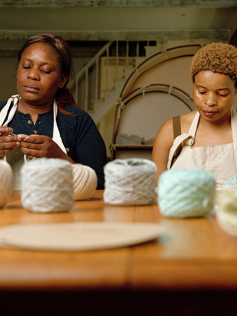 Earth Age makers crocheting at their Cape Town worktable, official studio photograph