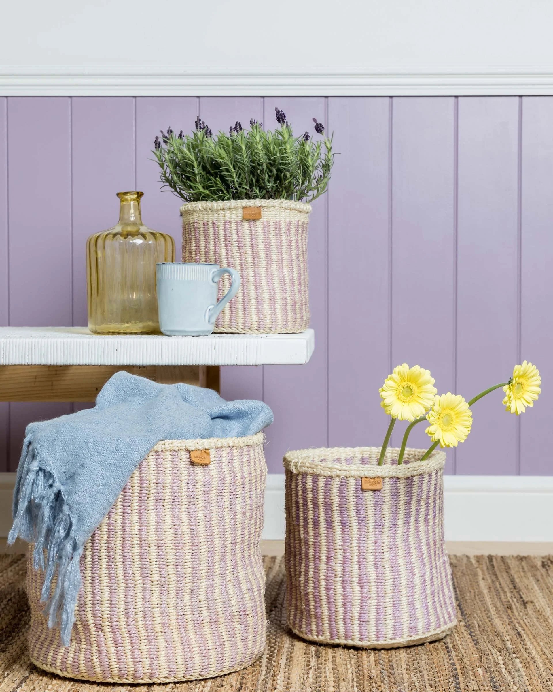 Official The Basket Room styling: lavender wall, wooden stool, plants and lavender striped baskets