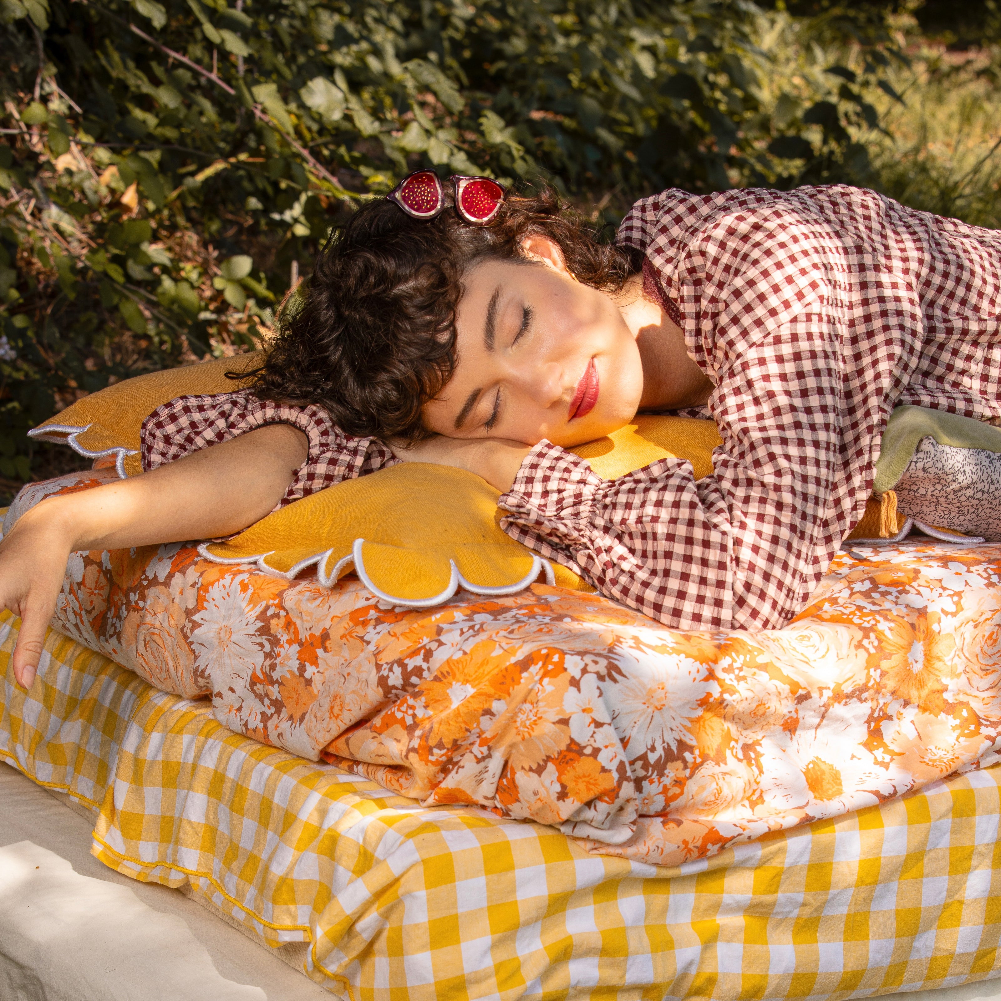 Official Coucou Suzette model wearing fig hair accessories, resting on floral and yellow gingham cushions